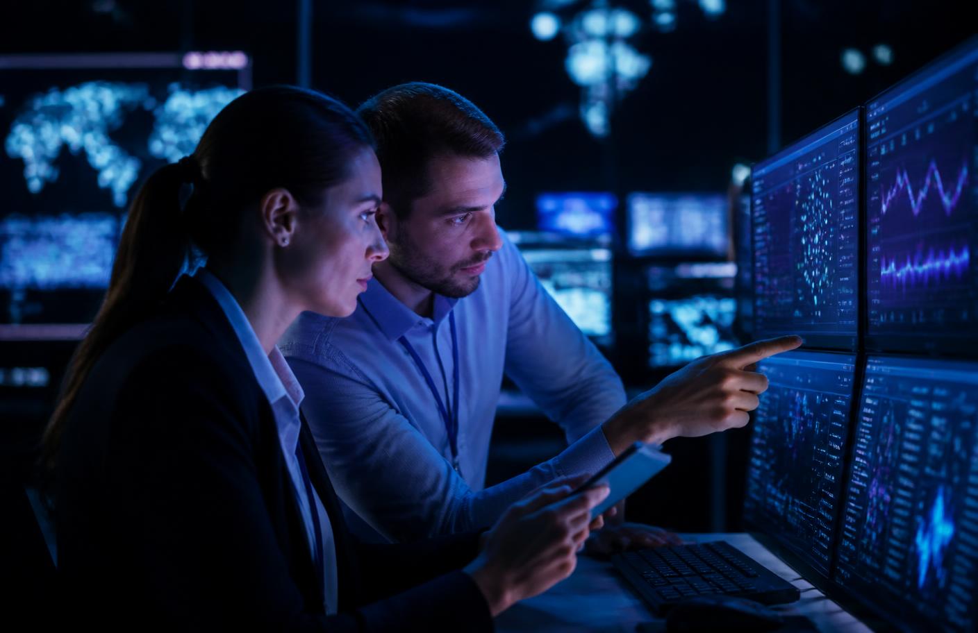 IT engineer monitoring systems on multiple screens